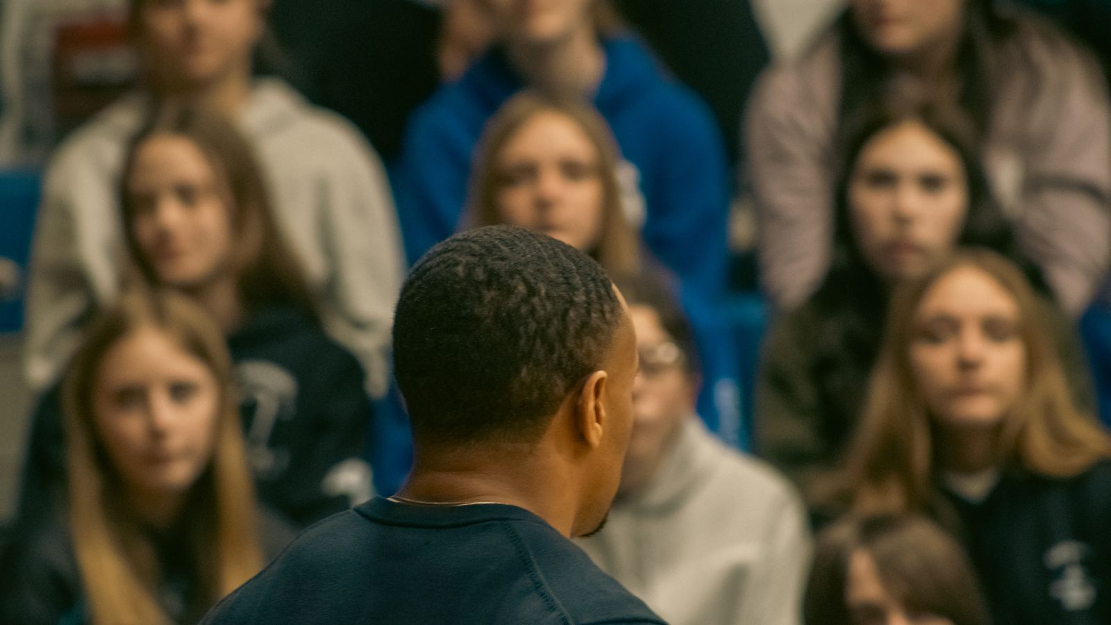 SMSB Inc. speaker addressing students seated in bleachers at a school assembly