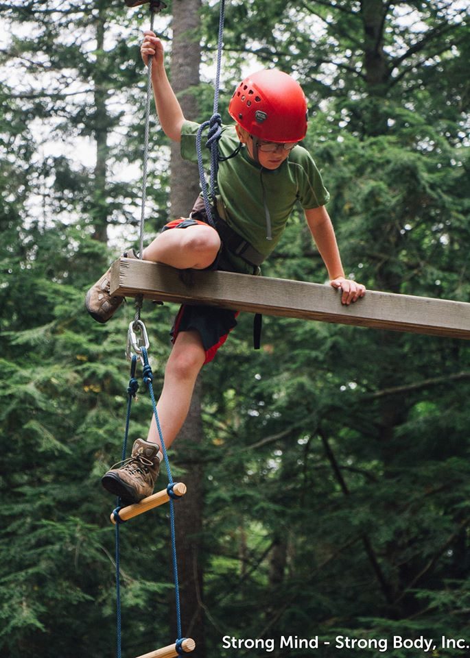 Youth completing an outdoor ropes course challenge